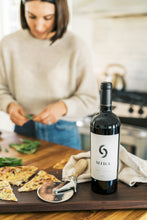 Load image into Gallery viewer, woman making pizza with wine in front