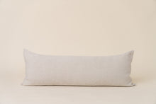 Load image into Gallery viewer, A long rectangular lumbar pillow with a neutral beige color and a subtle animal print, featuring a natural canvas backing with a hidden zipper and a vegan leather logo tag.